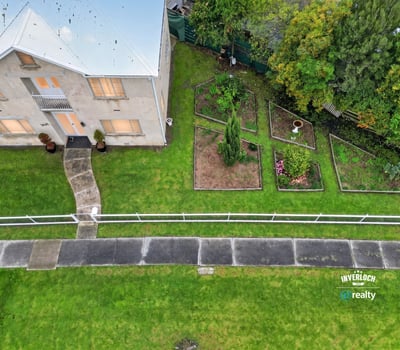 Spacious two-story home with expansive gardens, offering a unique outdoor living experience and plenty of potential.