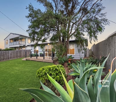 Spacious backyard with lush greenery, perfect for outdoor gatherings and relaxation near a modern home.