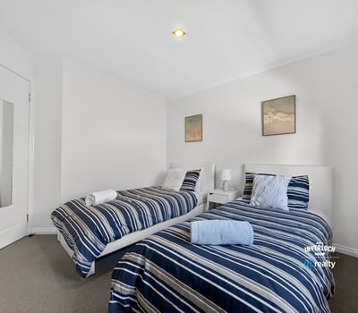 Bright and inviting twin bedroom featuring modern decor and comfortable furnishings for a relaxing stay.
