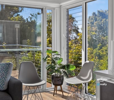 Bright and airy living space featuring large windows and a balcony with lush outdoor views.