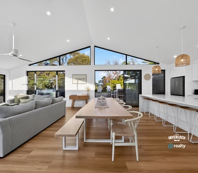 Bright and open living space seamlessly connects dining and kitchen areas, featuring large windows with natural light.