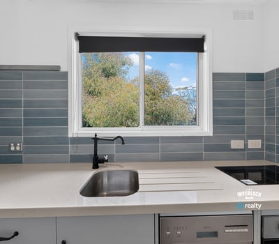 Modern kitchen featuring sleek countertops and a large window that offers refreshing garden views.