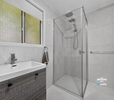 Modern bathroom featuring a walk-in shower and sleek cabinetry, designed for functionality and comfort.