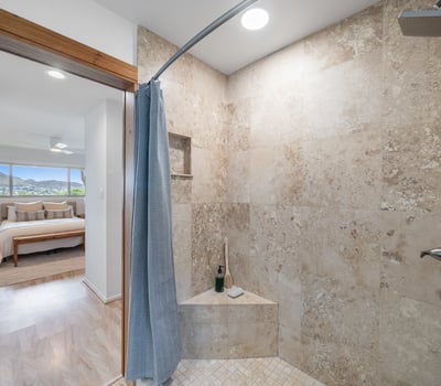Bright and spacious bathroom with natural stone finishes, featuring a walk-in shower and scenic views.