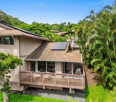 Welcoming home surrounded by lush greenery, featuring a spacious deck and sustainable solar energy options.
