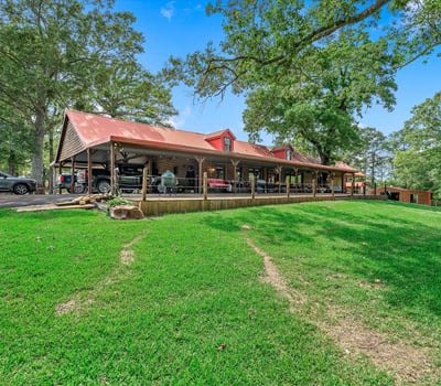 Spacious property featuring a large covered porch, surrounded by lush greenery and scenic views.