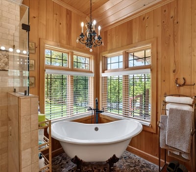 Experience a bright, inviting bathroom featuring a freestanding tub and large windows with scenic views.