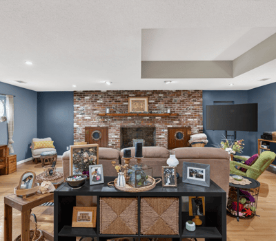 Spacious living area featuring exposed brick accents, ample natural light, and versatile entertainment options.