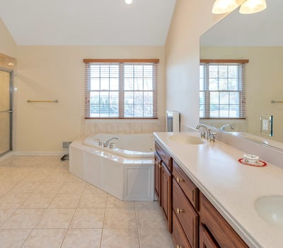 Primary Bathroom has a beautifully tiled shower, high ceiling with recessed lighting, and natural light.