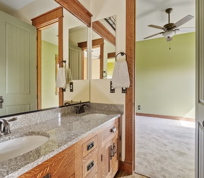 Shared bathroom featuring dual sinks, granite counters, and custom cabinetry. Thoughtfully designed for functionality while maintaining upscale finishes.