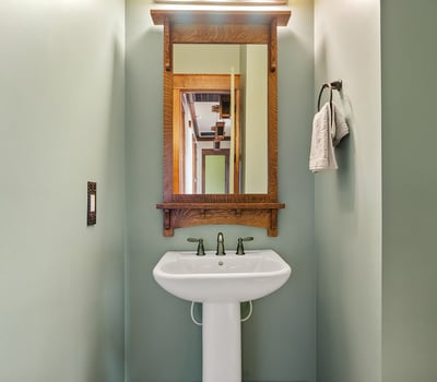 Designer half bath with pedestal sink, custom mirror, and handcrafted wood accents. A polished space that adds charm and convenience for visitors.