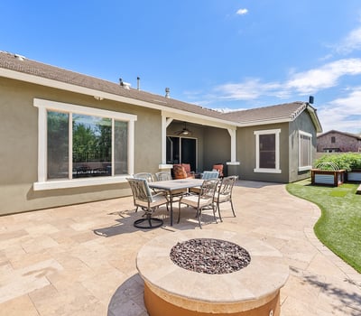 This expansive paver backyard offers a perfect blend of function and fun with its built-in BBQ, firepit, and seating for gatherings under the Arizona sky.