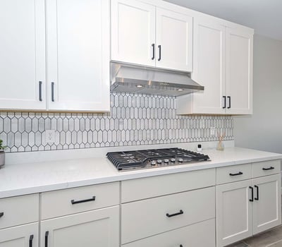 A stunning combo of form and function with a built-in gas cooktop, vertical tile backsplash, and crisp white cabinetry designed for serious home chefs.