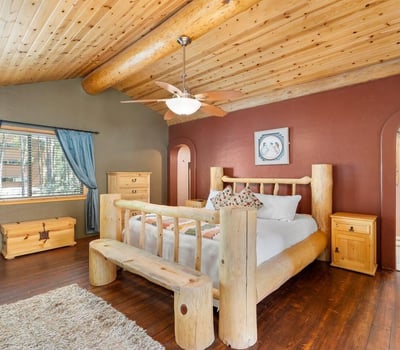 Spacious primary bedroom showcasing vaulted ceilings, rustic log craftsmanship, and an open loft-style overlook that adds character and architectural interest.