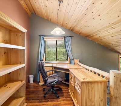 Dedicated loft office featuring built-in shelving, wood finishes, and natural light perfect for a quiet workspace within this Prescott log home.