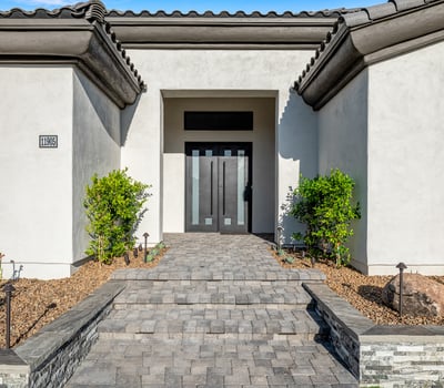 A modern stone-paved entry leads to sleek double doors, giving this Scottsdale property standout curb appeal.
