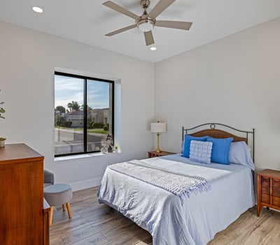Comfortable guest bedroom with clean design, wood-look floors, and fan lighting enhances this Scottsdale home s appeal.
