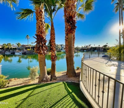 Resort-style backyard featuring a pristine pool and elevated patio overlooking calm blue waters perfect for entertaining or relaxing outdoors.