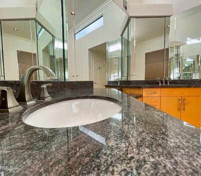 Rich granite countertops and modern hardware bring timeless appeal to this refined bathroom design.