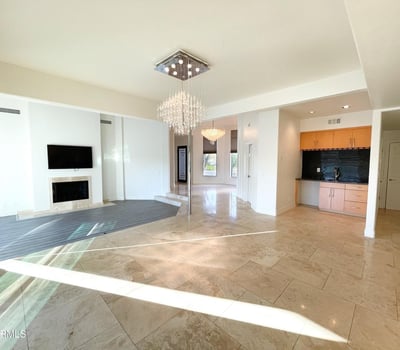 Open-plan living and dining area with glossy tile floors, recessed lighting, and a convenient wet bar for easy entertaining.