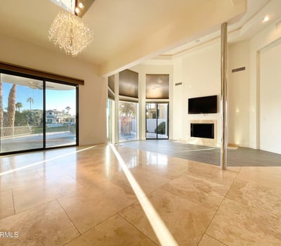 Beautifully designed living room with abundant sunlight, crystal chandelier, and sliding glass doors leading to the lakefront patio.