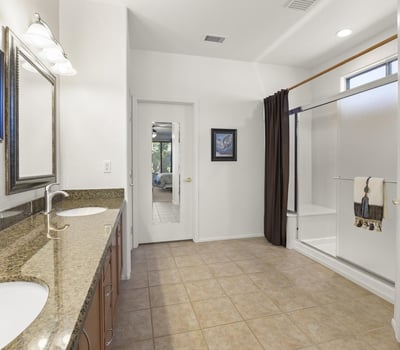 Dual-sink granite vanity and framed mirrors create a polished, spa-inspired space designed for comfort and convenience.
