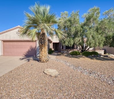 This charming front exterior showcases desert landscaping, mature trees, and timeless curb appeal an ideal first impression in Surprise.