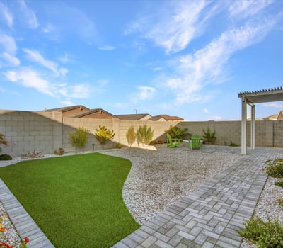 A beautifully landscaped yard with turf, garden beds, and open seating areas gives homeowners a private outdoor retreat in Litchfield Park.