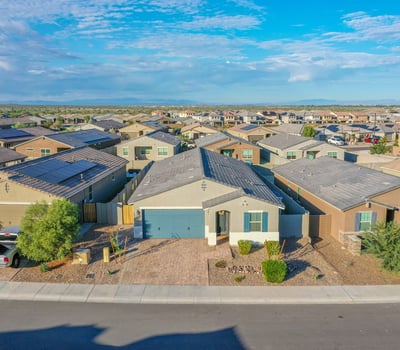 Drone-angle front view showcasing the home s attractive fa ade, paver driveway, and desert-friendly landscaping. Strong curb appeal in a desirable setting.