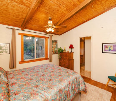 This restful primary bedroom showcases warm wood ceilings, soft textures, and scenic outdoor views. Its rustic charm reflects the essence of quiet living in Hackberry s desert landscape.
