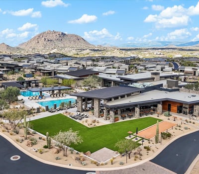 Aerial showcase of the Sereno Canyon clubhouse featuring resort-style pools, modern design, and expansive mountain scenery within a guard-gated Scottsdale community.
