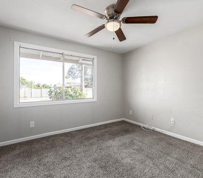 Spacious secondary bedroom with ceiling fan and soft carpeting perfect for guests or a dedicated workspace in this Phoenix property for sale.