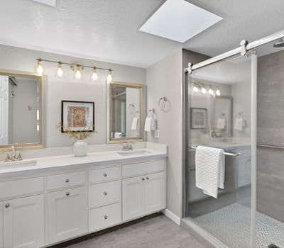 Updated bathroom featuring dual sinks, walk-in shower, modern tile, and stylish fixtures for a spa-like feel.