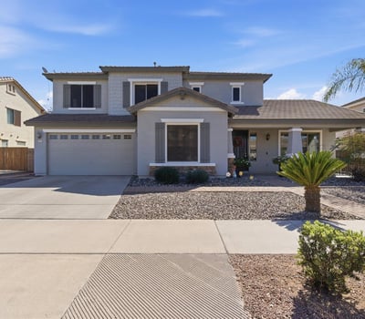 Attractive exterior of this Queen Creek property featuring a covered entry, desert landscaping, and attached garage in the popular Cortina community.