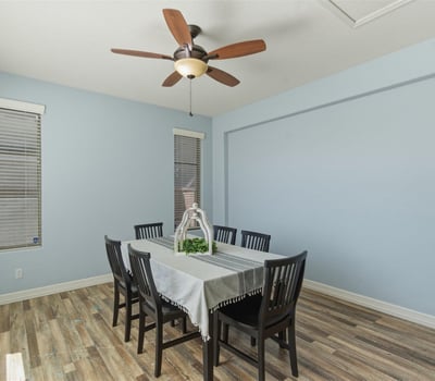 Bright dining room with wood-style flooring, ceiling fan, and neutral walls creating a welcoming setting for gatherings and meals.