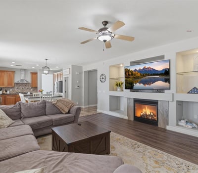 Stylish living area featuring a fireplace with decorative niches, ceiling fans, and durable wood-style flooring throughout the main living space.
