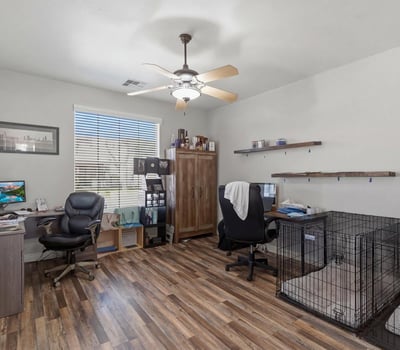Spacious office area with wood-style flooring and large window, ideal for remote work, study, or a hobby room within this Queen Creek home.