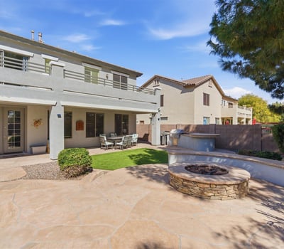 Backyard entertaining area featuring a built-in fire pit, spacious patio, and landscaped yard with pool views perfect for gatherings.