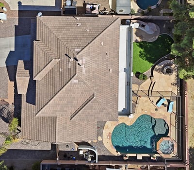 Direct overhead aerial showcasing the backyard design with pool, spa, patio seating areas, and landscaped yard perfect for outdoor entertaining in Queen Creek.
