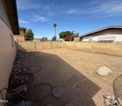 Expansive backyard area with low-maintenance desert landscaping and block wall fencing. The generous outdoor space offers flexibility for entertaining, recreation, or customizing future landscaping.