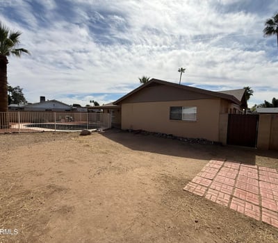 Rear exterior view highlighting the covered patio, fenced pool, and spacious yard. The layout provides a welcoming outdoor setting ideal for relaxing evenings and weekend gatherings.