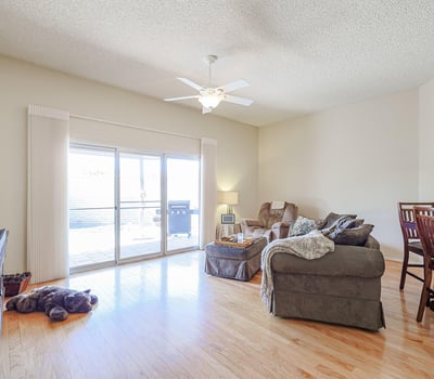 Open-concept living area with hardwood floors, ceiling fan, and large sliding doors leading to the backyard patio for indoor-outdoor living.
