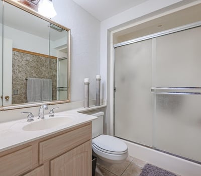 Primary bathroom with walk-in shower, large vanity, and bright lighting, designed for functionality and comfort in this Sun City property.