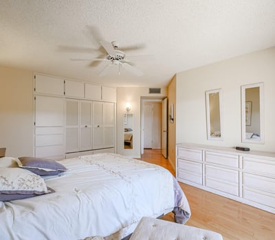 Secondary bedroom with built-in cabinets, hardwood floors, and ample closet space, ideal for guests or flexible living needs.