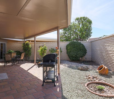 Low-maintenance backyard with desert landscaping, privacy walls, and covered patio, offering a peaceful outdoor retreat.