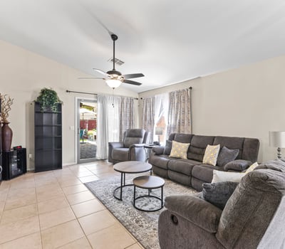 Spacious family room with sliding door leading to the backyard, ceiling fan, and open design for seamless indoor-outdoor living.