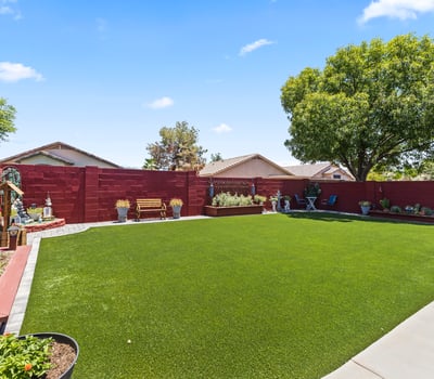 Spacious yard with artificial turf, raised garden beds, and decorative landscaping. Ideal for gardening and outdoor enjoyment.