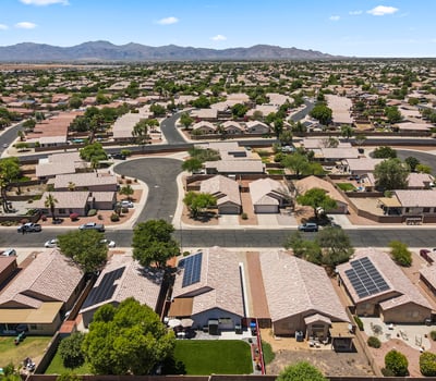 Sweeping aerial view of the neighborhood featuring organized streets, nearby homes, and distant mountain scenery, offering a sense of location and community.