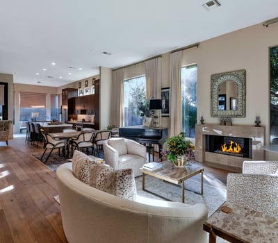 Spacious living area with high ceilings, wood floors, and a modern fireplace creating a warm and inviting atmosphere in this Phoenix home designed for entertaining.