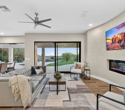 Open-concept living room with sleek fireplace, wood floors, and sliding doors leading to the backyard, showcasing Scottsdale indoor-outdoor design.